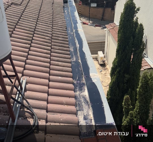 איטום גג עם חומר איטום שחור על רעפים